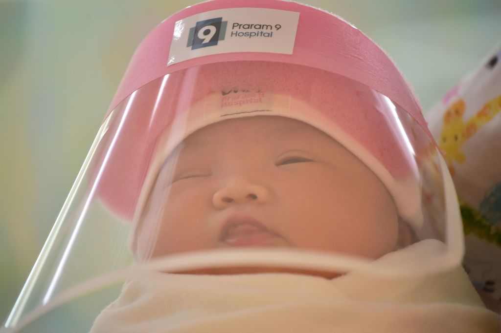 This photo taken through a glass window at a maternity ward shows a newborn baby wearing a face shield, in an effort to halt the spread of the COVID-19 coronavirus, at Praram 9 Hospital in Bangkok on April 9, 2020.
