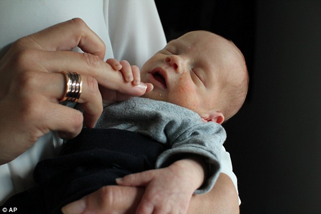 Cute: Vincent, the first baby born to a woman who had a womb transplant, is cradled by his mother in Sweden