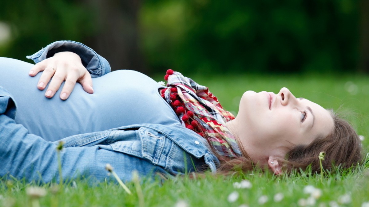 Беременная женщина лежит на траве