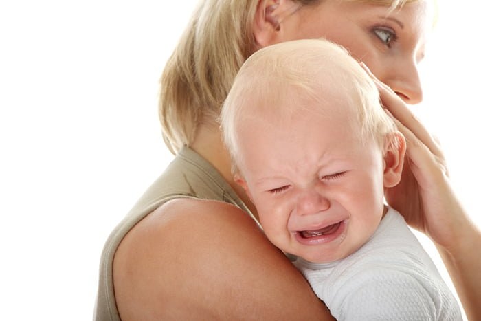 мама держит плачущего малыша на руках
